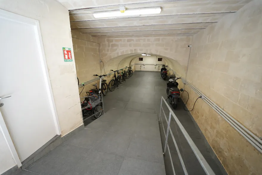 L’interno con biciclette e scooter parcheggiati a terra lungo la parete