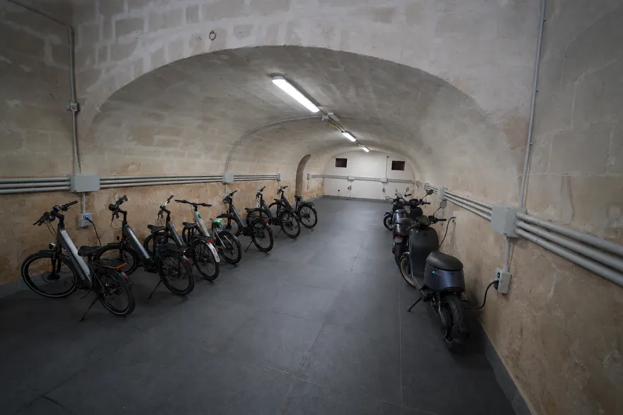 Biciclette e scooter allineati sotto la volta illuminata
