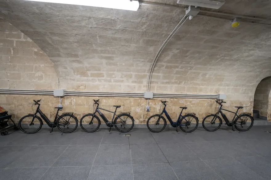 Una fila di biciclette elettriche contro il muro in tufo